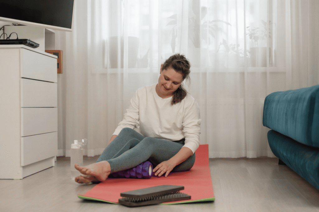 A woman is using a foam roller for muscle recovery and mobility.