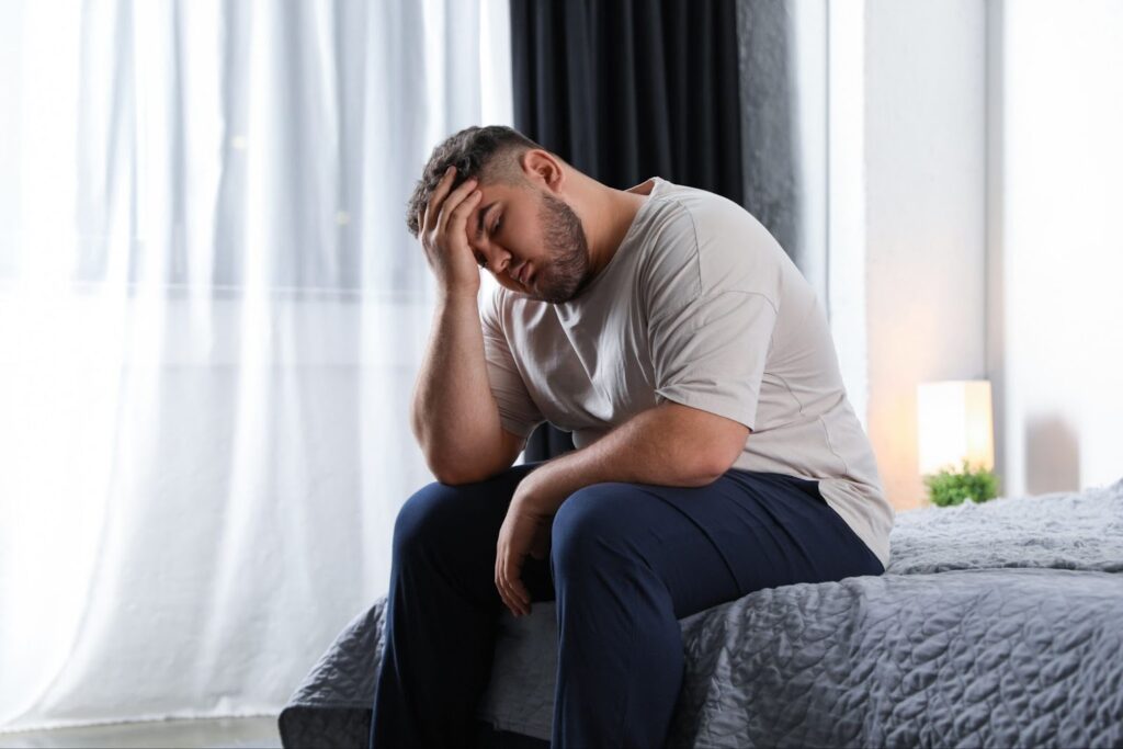 An overweight man due to an imbalance of ghrelin and leptin caused by sleep deprivation.